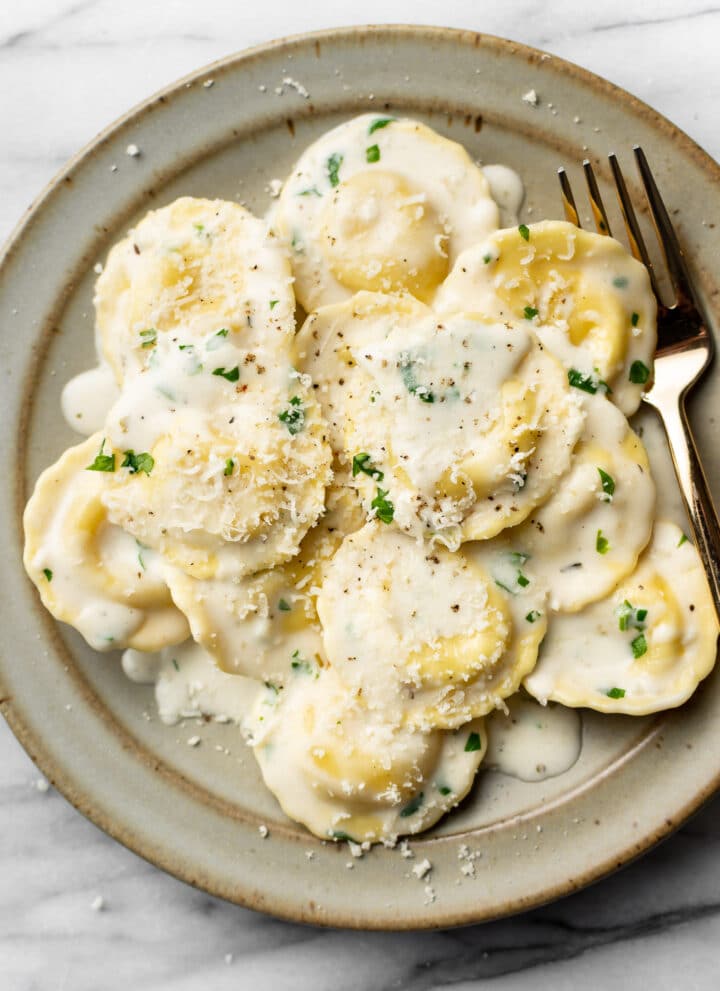a bowl of ravioli in cream sauce with a fork