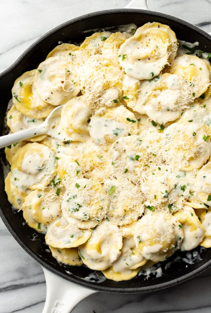 a skillet with ravioli in a white wine cream sauce