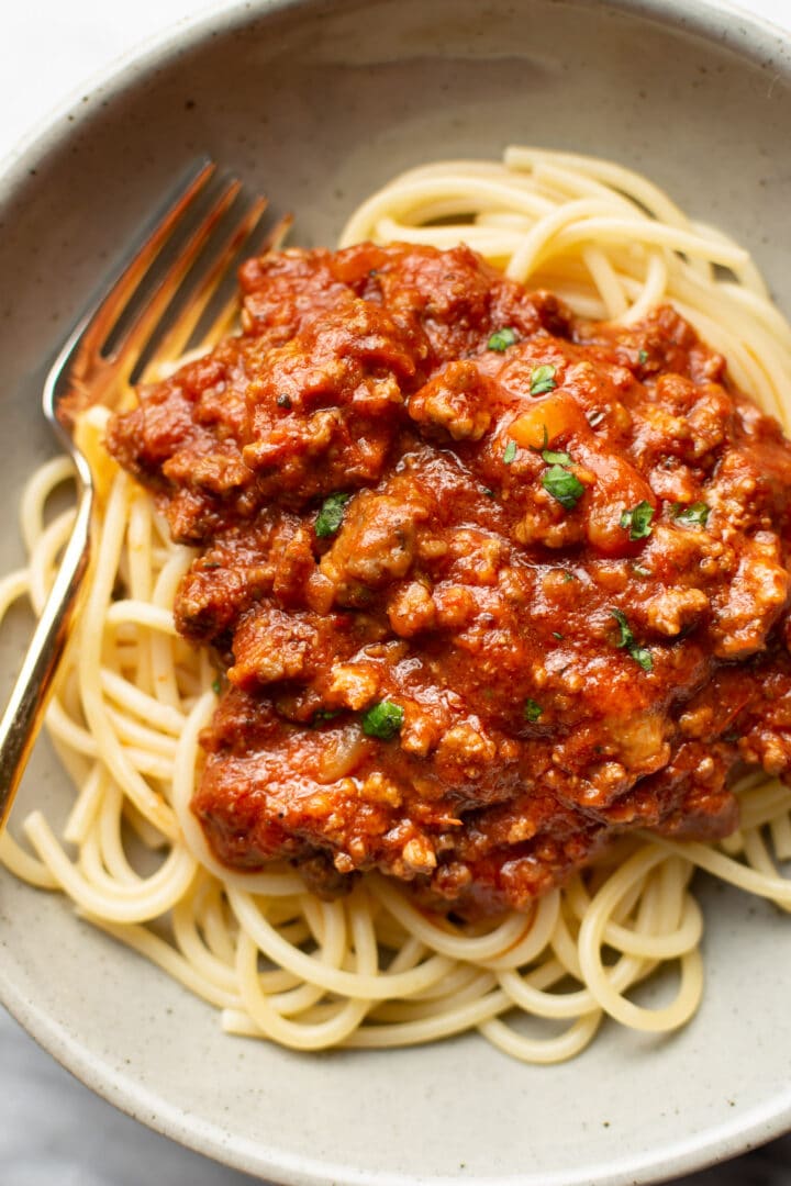 a bowl of spaghetti with meat sauce and a fork