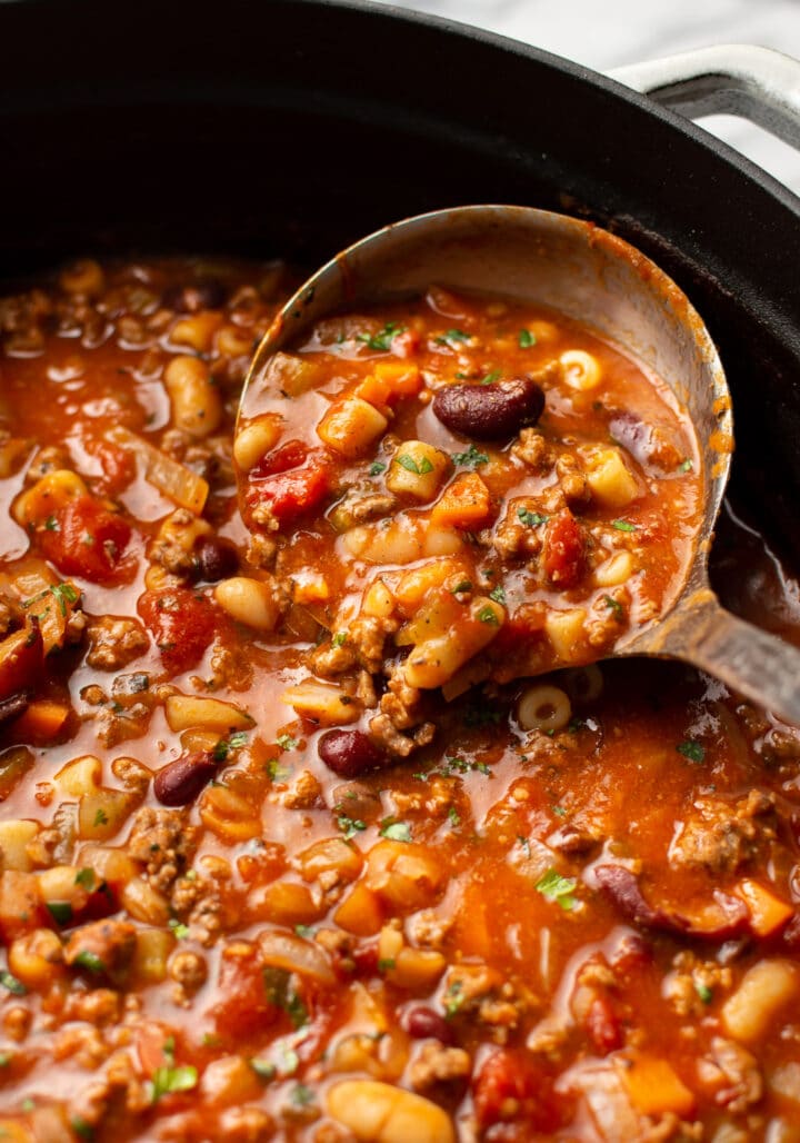 a ladle in a pot of pasta e fagioli soup