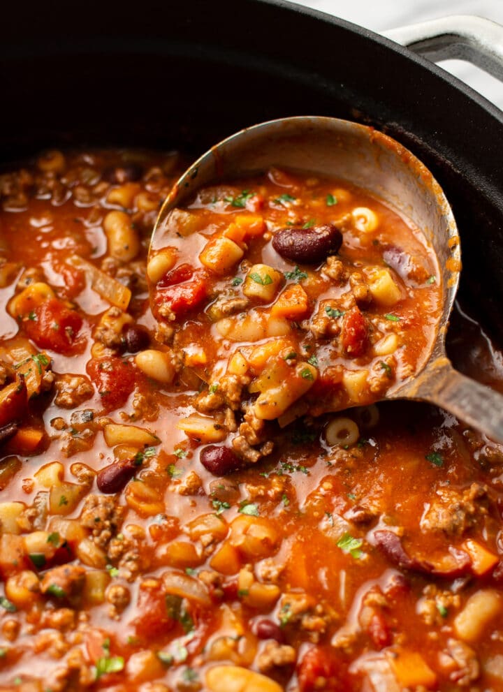 a ladle in a pot of pasta e fagioli soup
