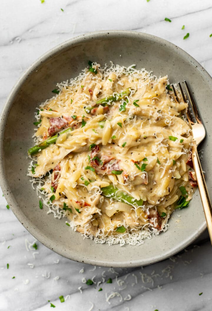 a bowl of pesto orzo with a fork