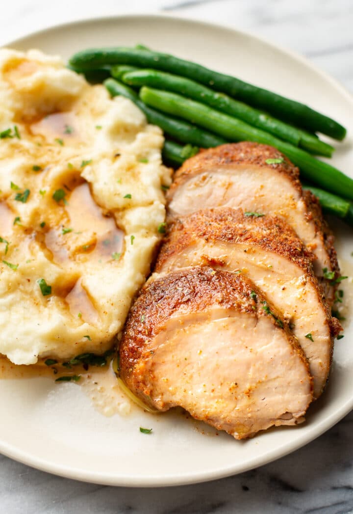 a plate with baked pork tenderloin, green beans, and mashed potatoes