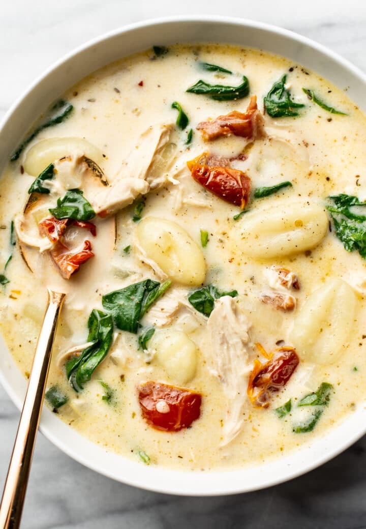 a bowl of tuscan chicken gnocchi soup with a spoon