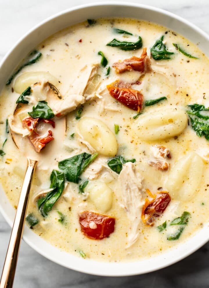 a bowl of tuscan chicken gnocchi soup with a spoon