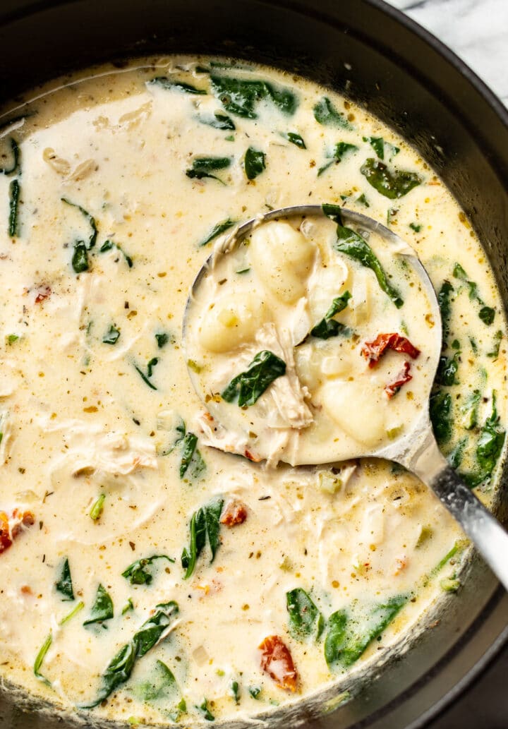 a pot of tuscan chicken gnocchi soup with a ladle