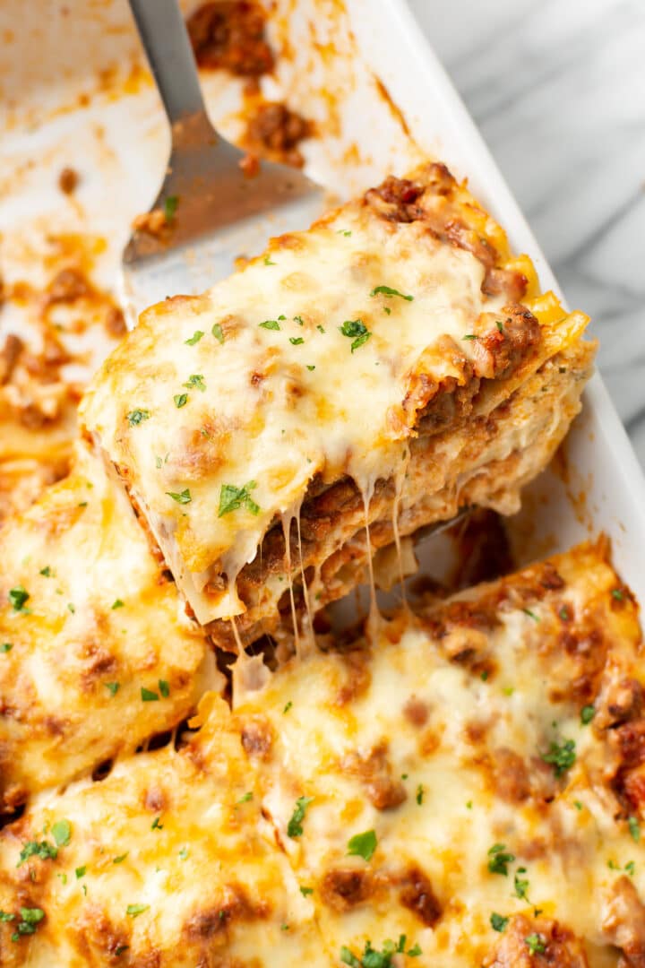 a spatula lifting a portion of lasagna from a baking dish