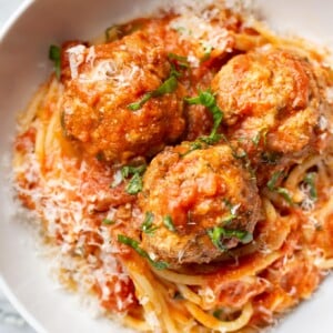 a bowl of spaghetti and meatballs with parmesan