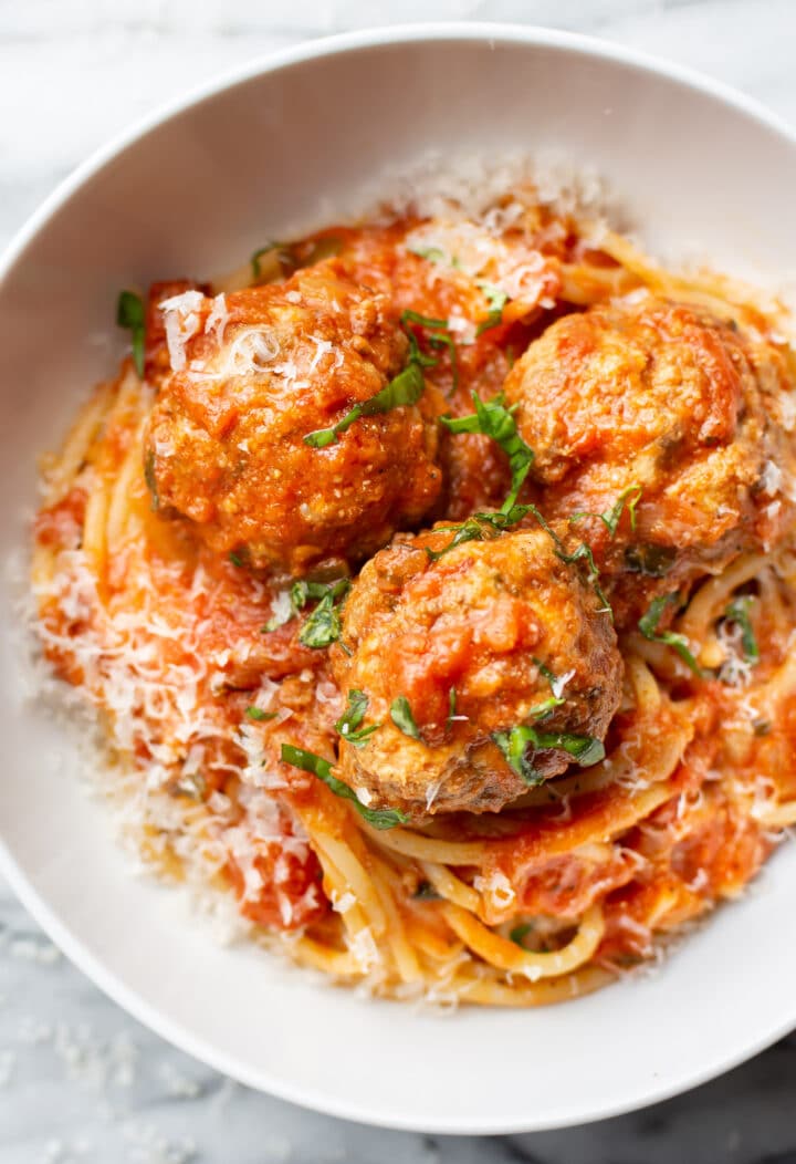 a bowl of spaghetti and meatballs with parmesan