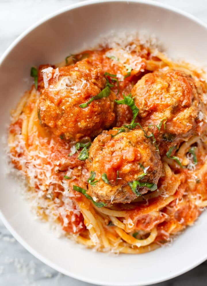 a bowl of spaghetti and meatballs with parmesan