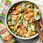a bowl of cajun chicken caesar salad next to tony chachere products