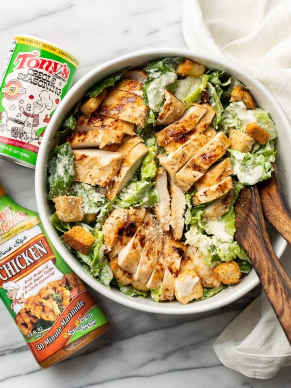 a bowl of cajun chicken caesar salad next to tony chachere products