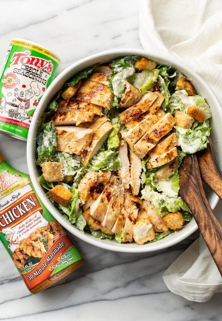 a bowl of cajun chicken caesar salad next to tony chachere products