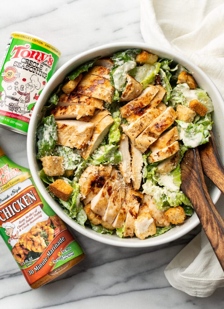 a bowl of cajun chicken caesar salad next to tony chachere products