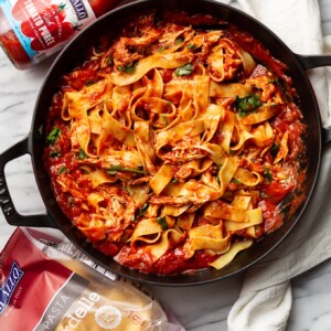 a braiser with chicken arrabiata pasta next to delallo products