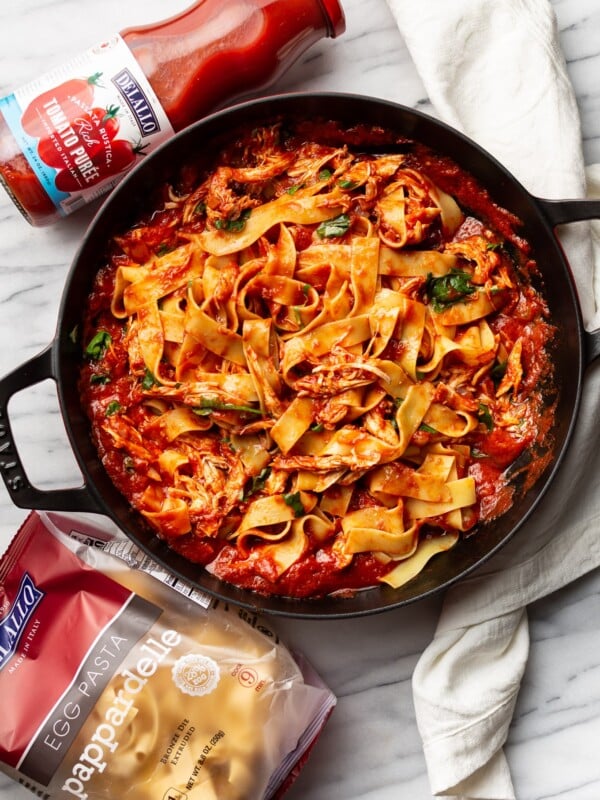 a braiser with chicken arrabiata pasta next to delallo products