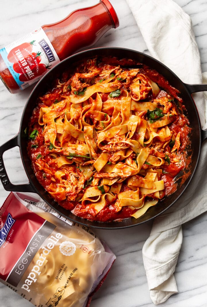 a braiser with chicken arrabiata pasta next to delallo products