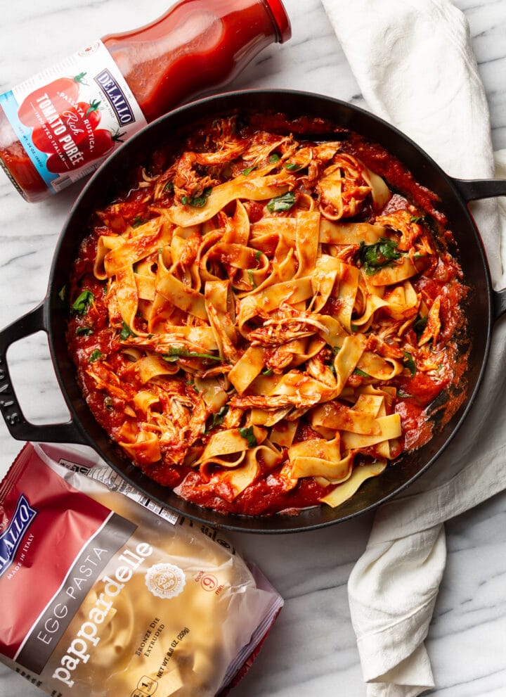 a braiser with chicken arrabiata pasta next to delallo products
