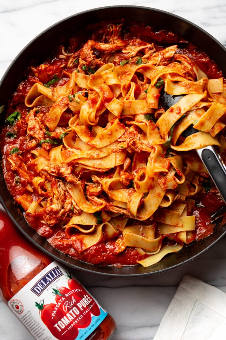 a braiser with chicken arrabiata pasta and serving tongs