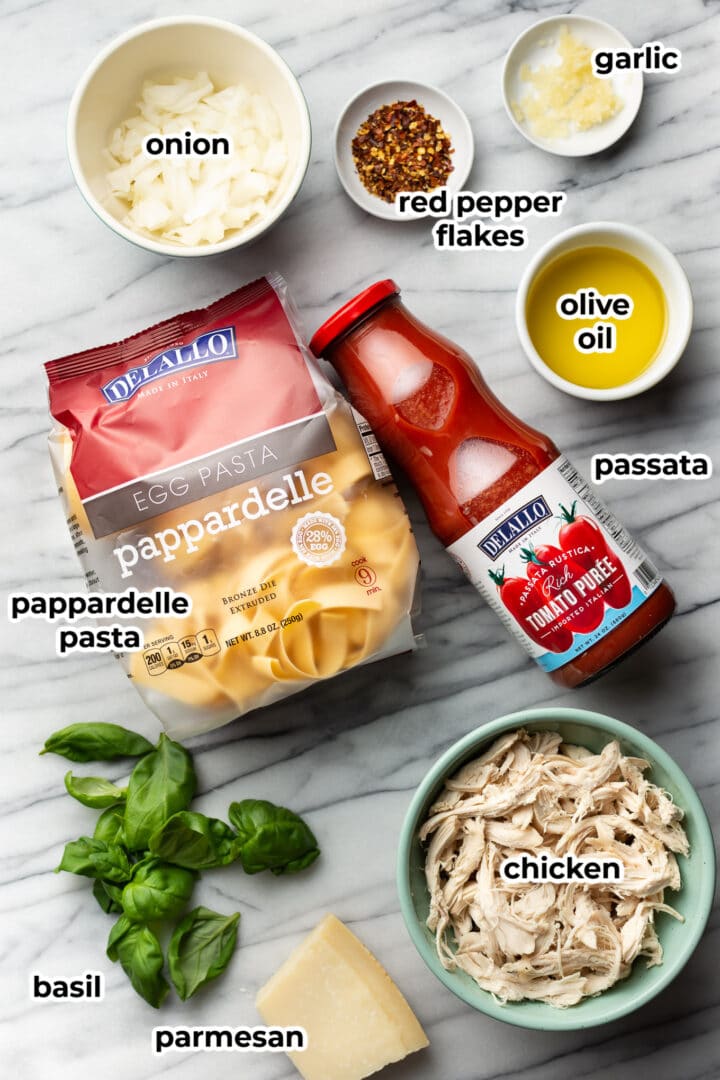 ingredients for chicken arrabiata pasta on a marble surface