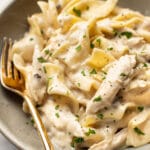 a bowl of chicken and noodles with a fork