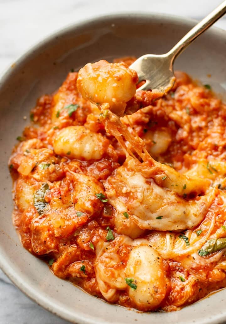 a bowl with cheesy baked gnocchi and a fork