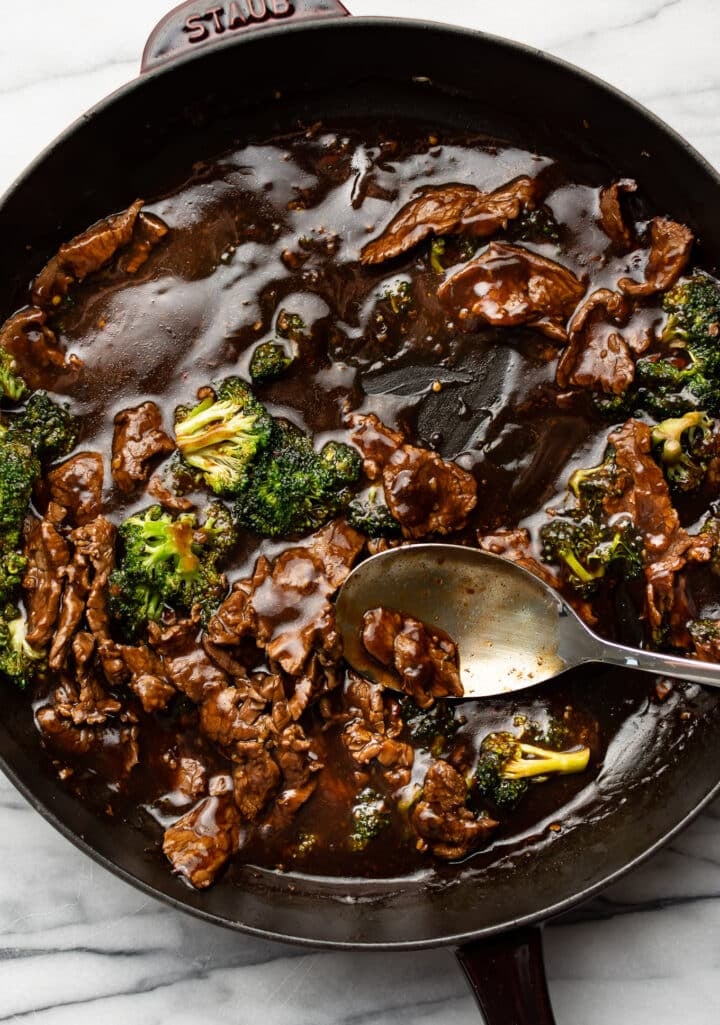 a cast iron skillet with beef and broccoli
