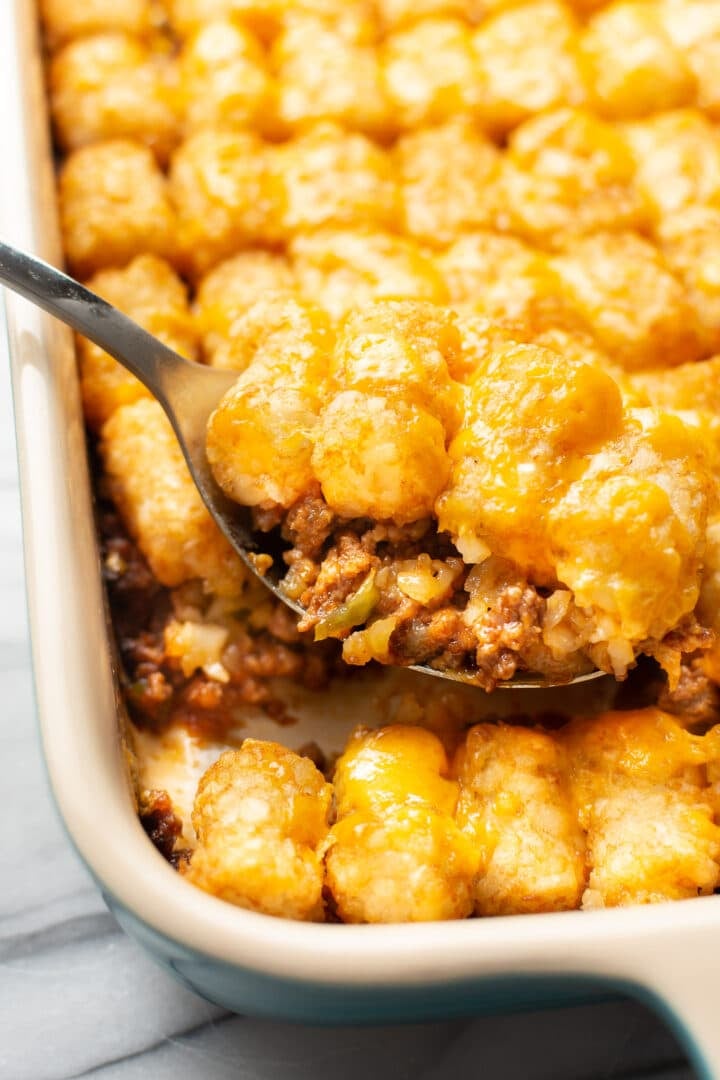 closeup of a baking dish with sloppy joe casserole and a serving spoon