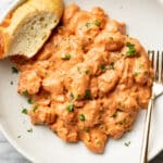 a bowl of gnocchi with a fork and slice of bread