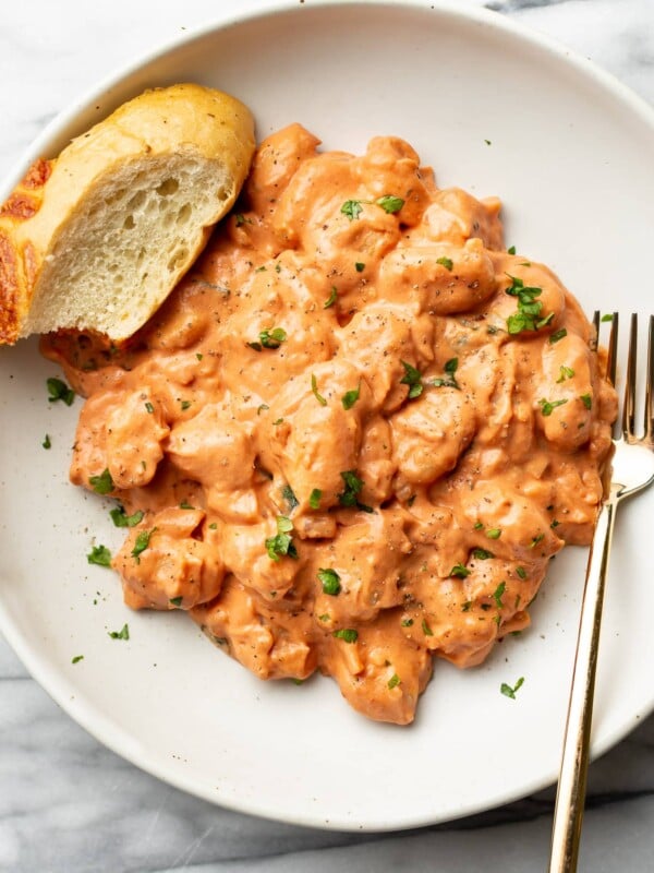 a bowl of gnocchi with a fork and slice of bread