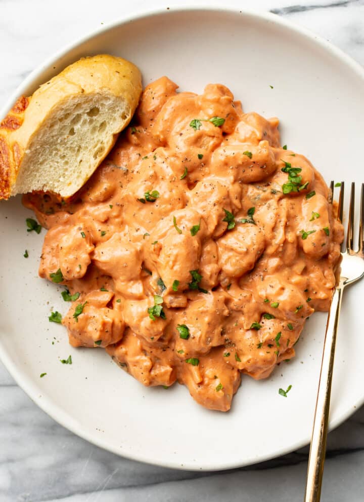 a bowl of gnocchi with a fork and slice of bread