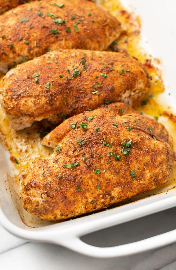 a baking dish with four baked chicken breasts