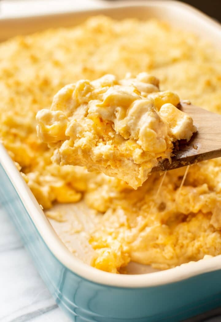 a baking dish with baked mac and cheese and a serving spoon