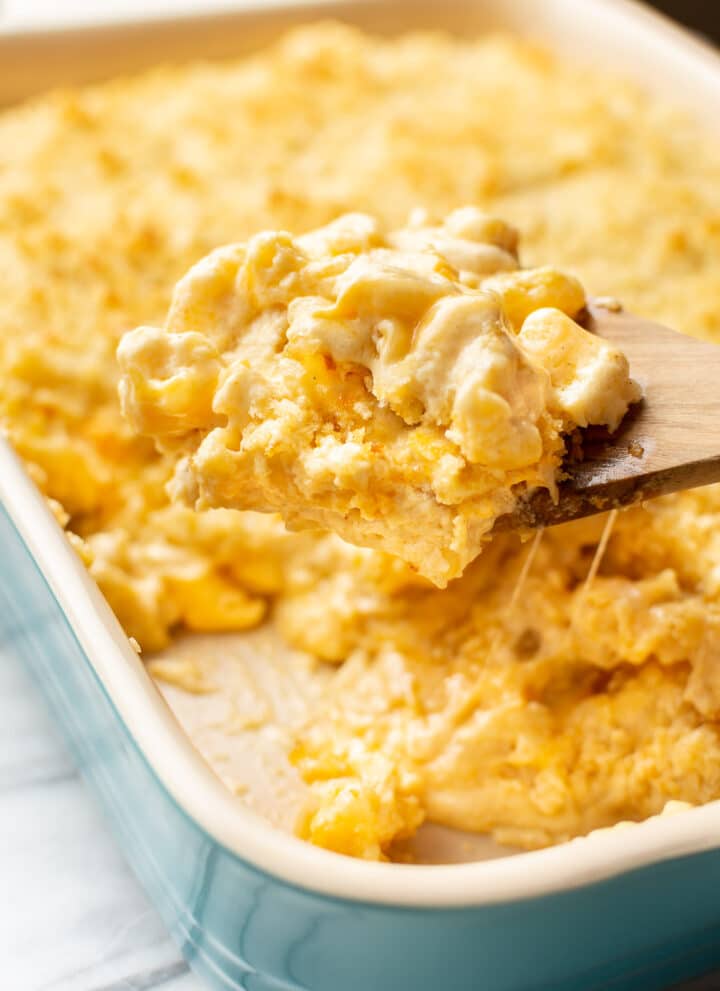 a baking dish with baked mac and cheese and a serving spoon