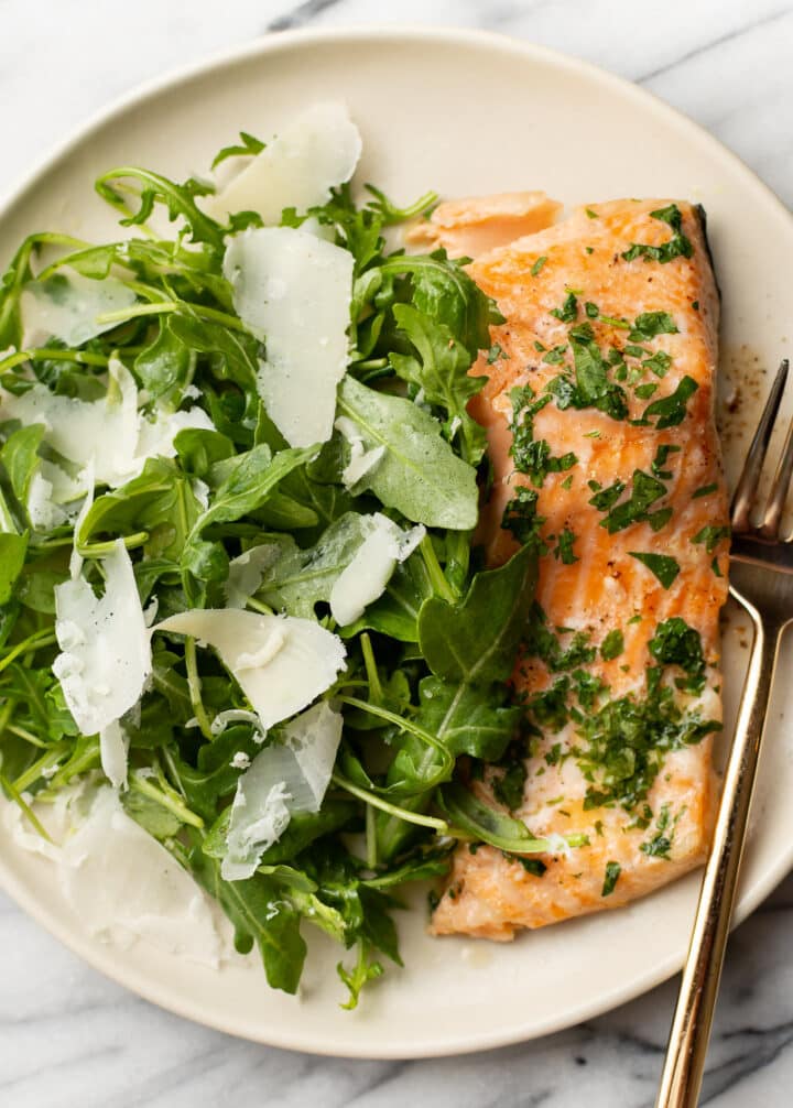 a plate with baked salmon and arugula salad