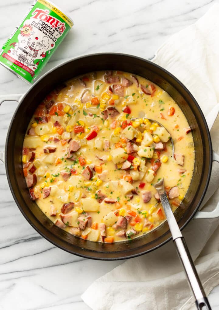 a pot of cajun corn chowder next to a can of tony chachere seasoning