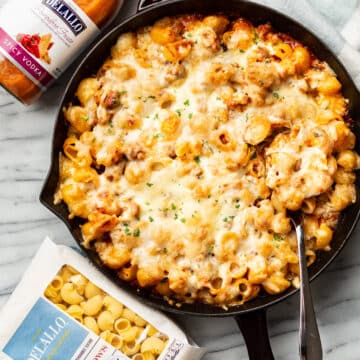 a skillet with spicy vodka pasta bake next to delallo products