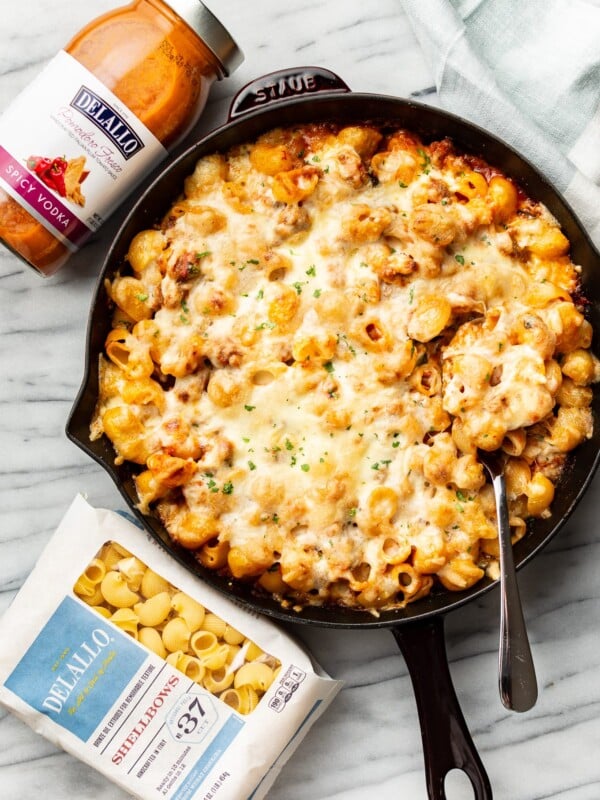 a skillet with spicy vodka pasta bake next to delallo products