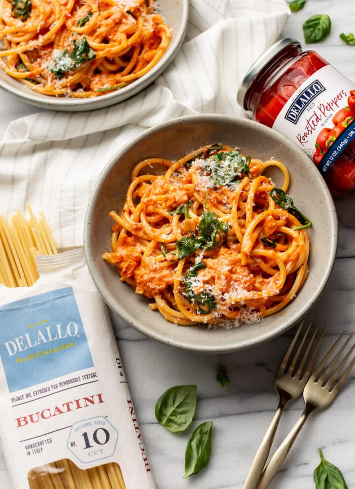 two bowls of creamy roasted red pepper pasta with delallo products