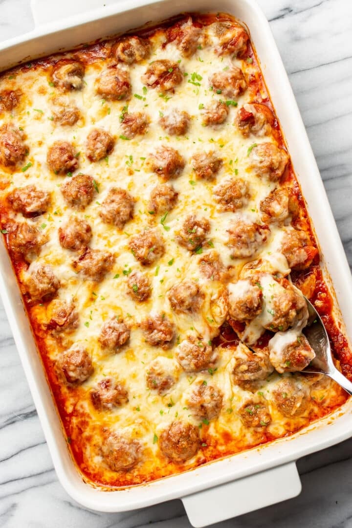 a casserole dish with baked meatballs and a serving spoon