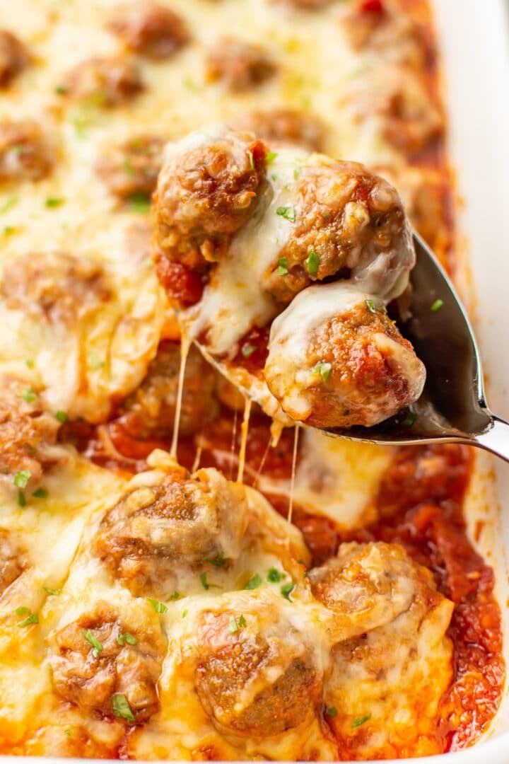 a serving spoon with cheesy baked meatballs