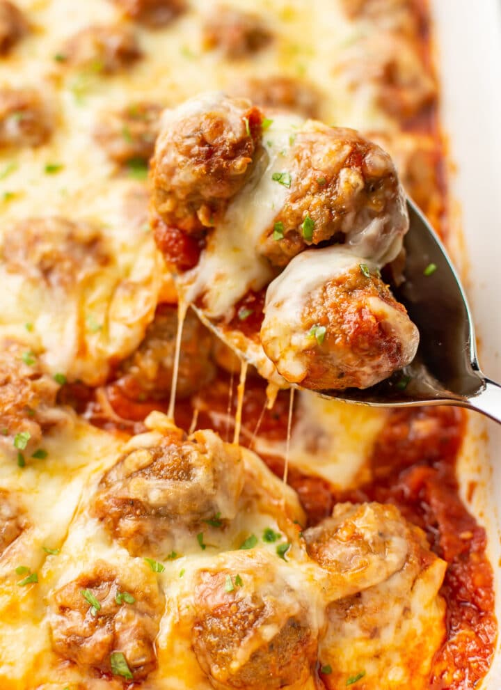 a serving spoon with cheesy baked meatballs