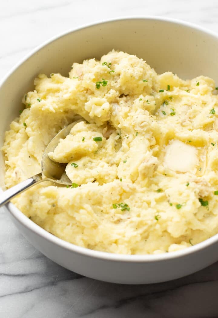 a bowl of boursin mashed potatoes with a serving spoon