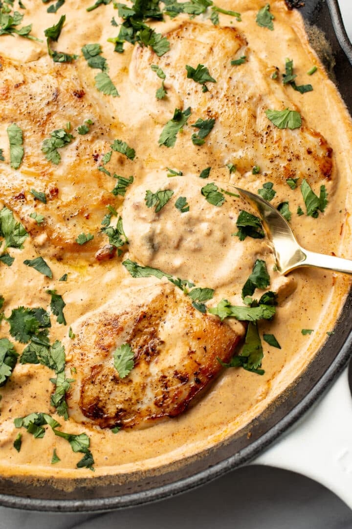 closeup of a skillet with creamy southwest chicken and a serving spoon