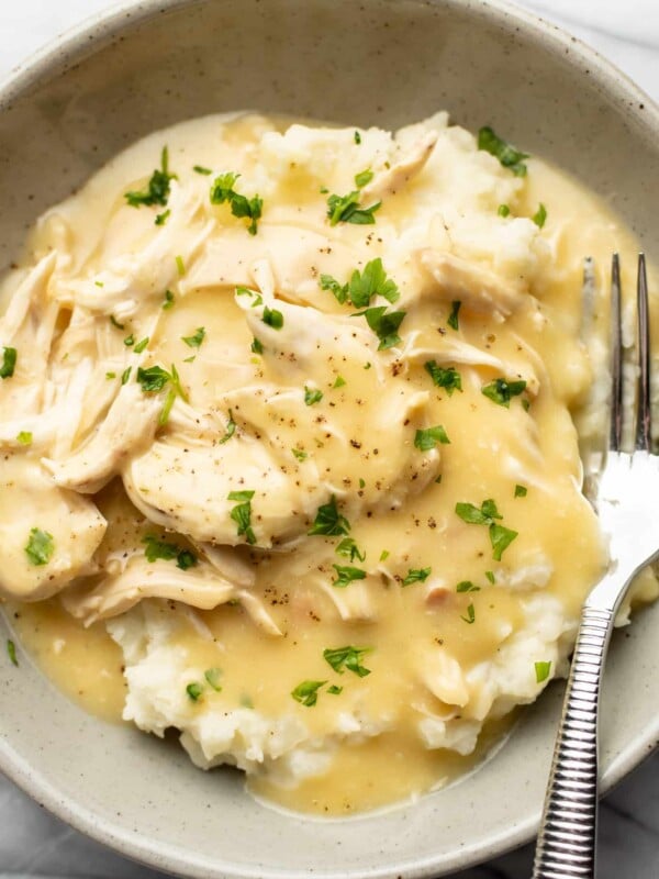 a bowl of shredded chicken and gravy over mashed potatoes