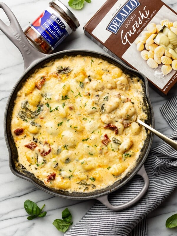 a skillet with tuscan baked gnocchi and a serving spoon