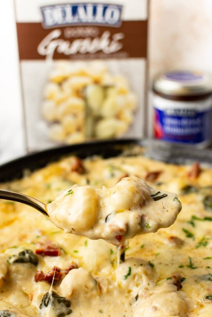 closeup of a spoonful of tuscan baked gnocchi over a skillet