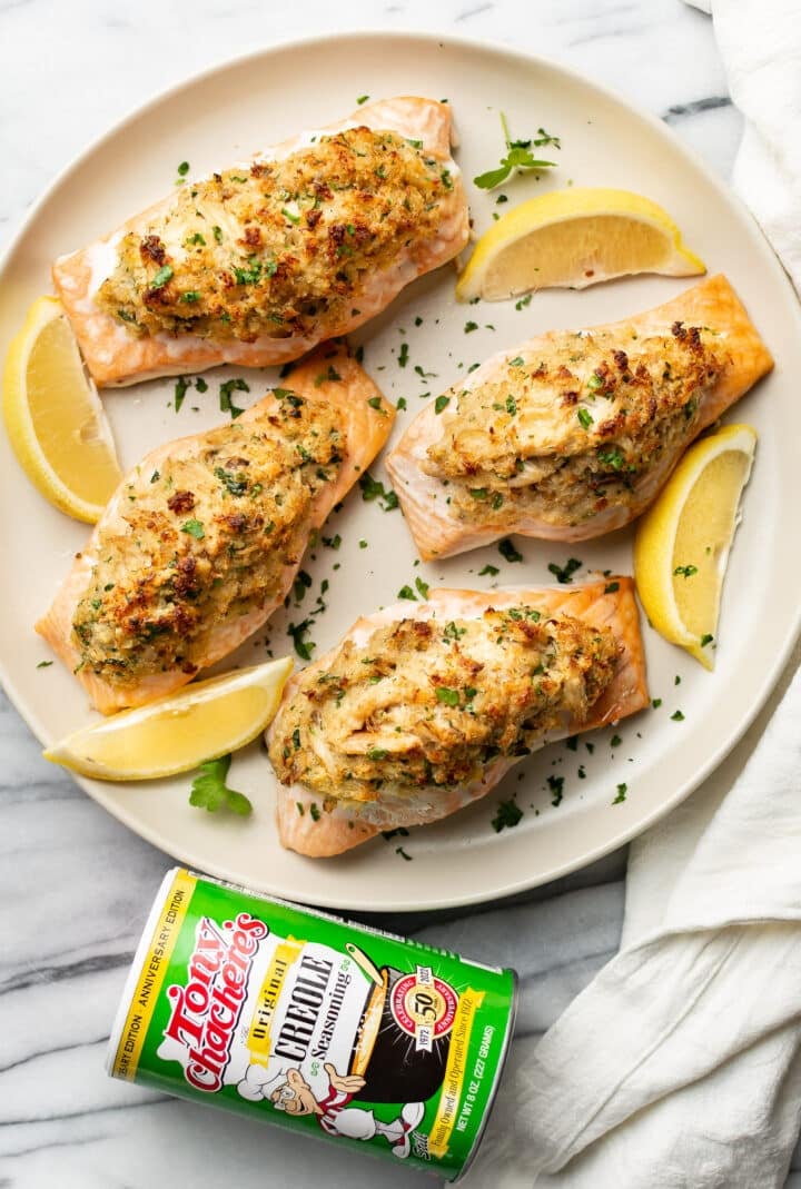 a plate of crab stuffed salmon next to a container of tony chachere's seasoning