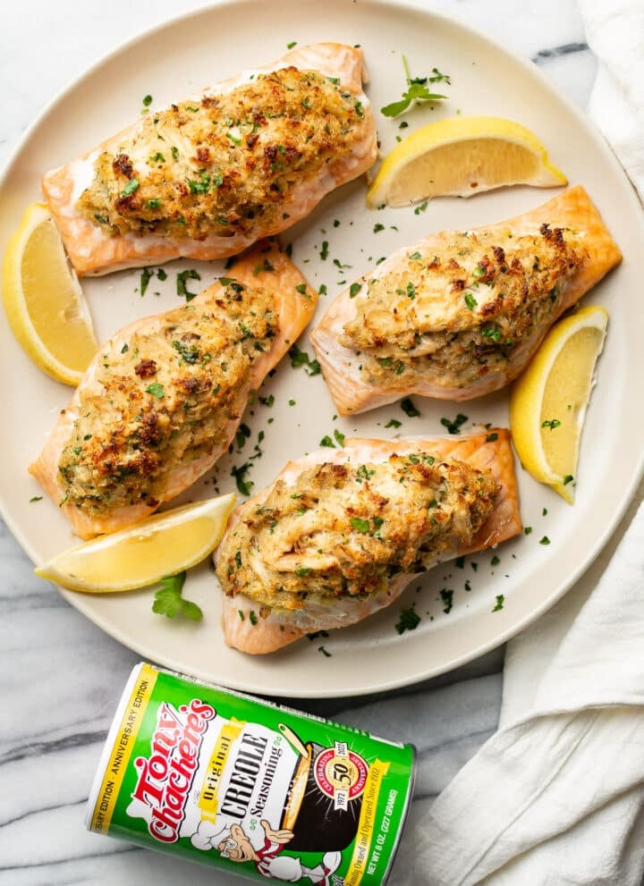 a plate of crab stuffed salmon next to a container of tony chachere's seasoning