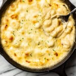 a skillet with cheesy gnocchi and a serving spoon